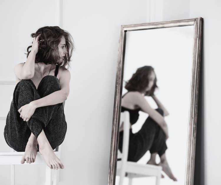 Person looking in the mirror at common ways we self sabotage